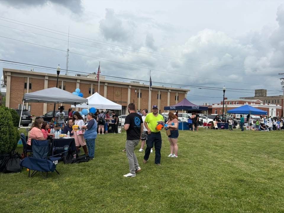 Attendees of the Pulaski County Spring Family Fun Festival standing in the grass beside the different booths